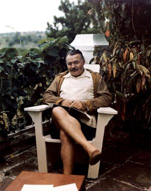 Ernest Hemingway sitting on a deck chair with a book at his home, Finca Vigia, San Francisco de Paula, Cuba.